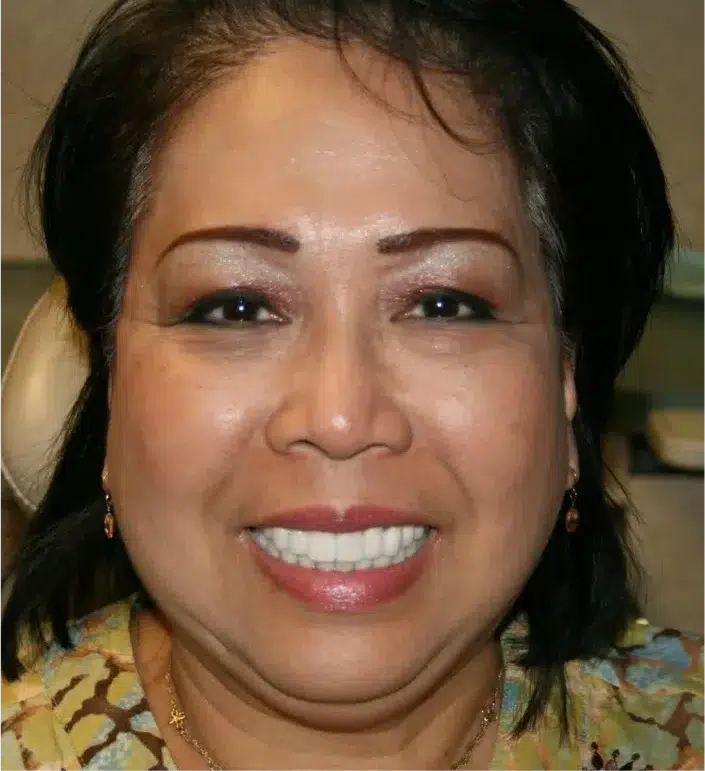 Smiling woman with short dark hair wearing patterned blouse and makeup
